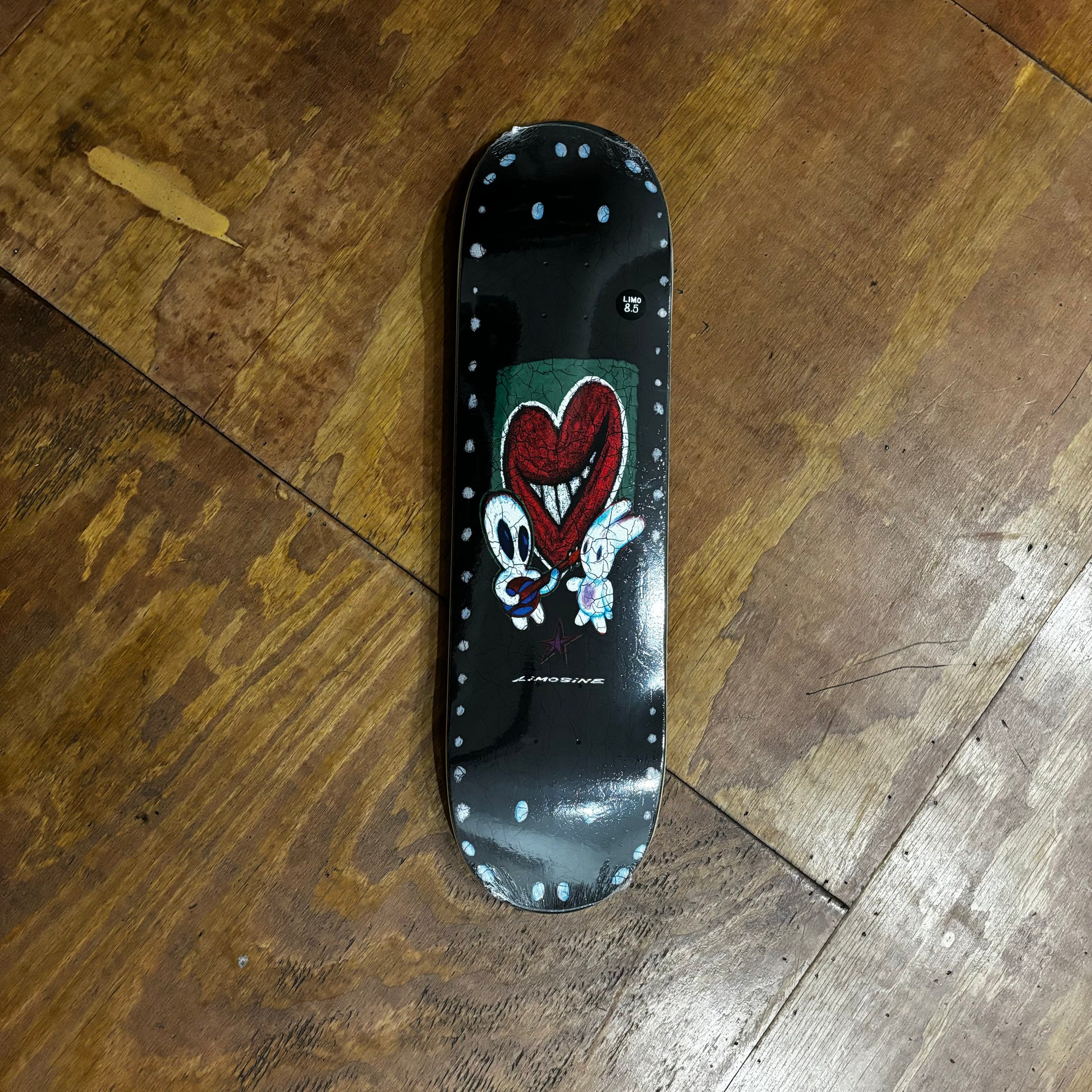 black, green and red heart graphic on skateboard deck