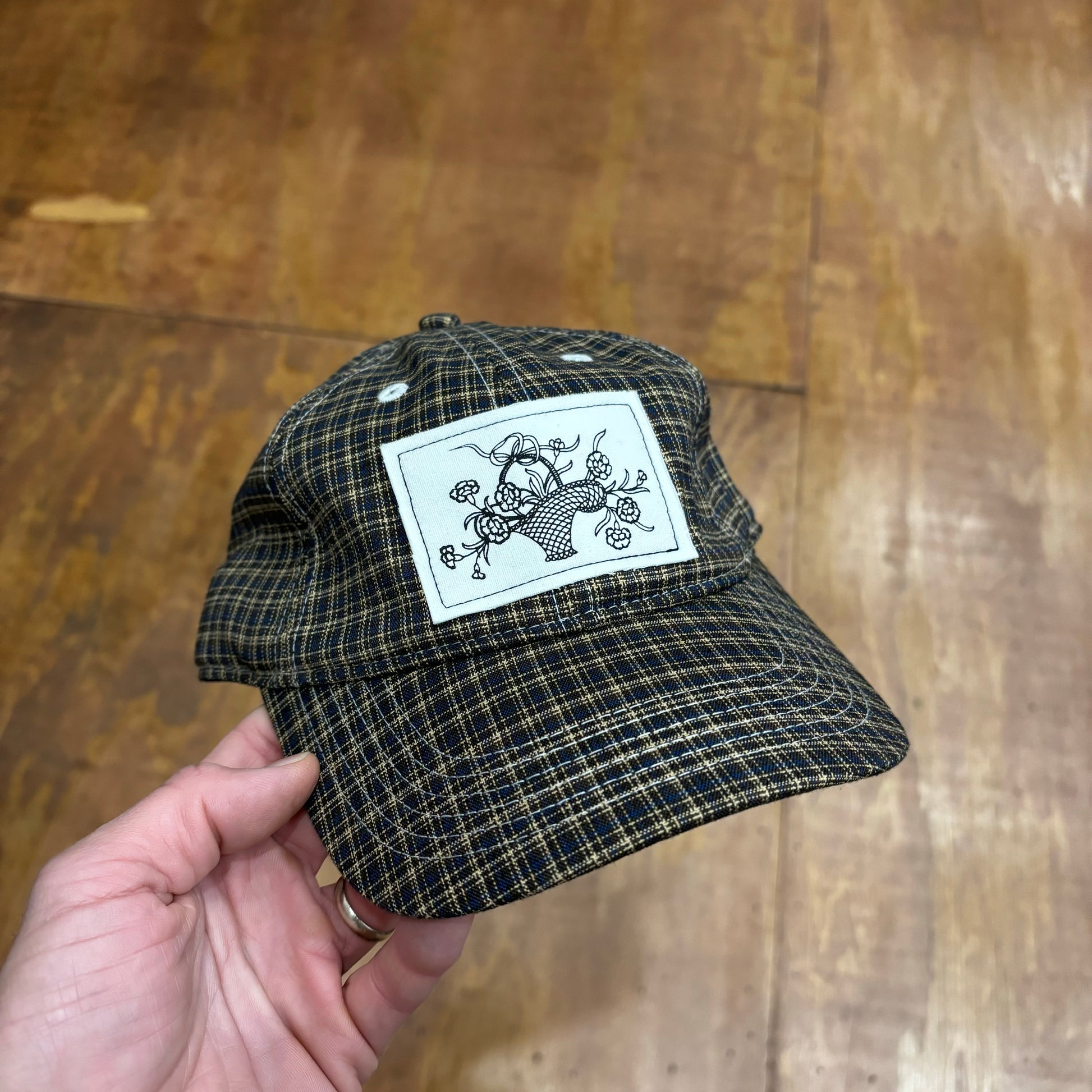 front view of plaid hat with large patch depicting a basket of flowers