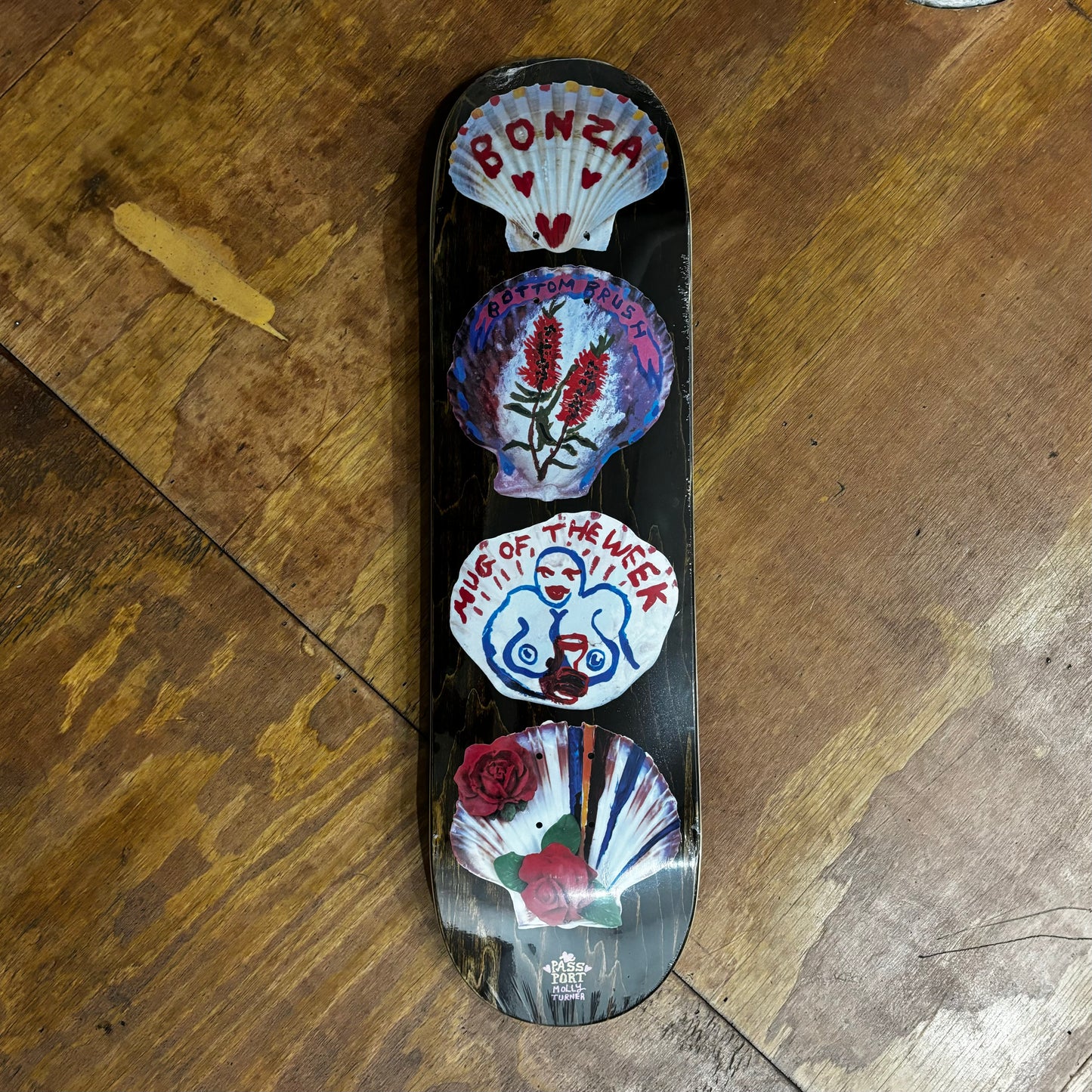 Image of four shells with hand drawn art on bottom of skateboard deck