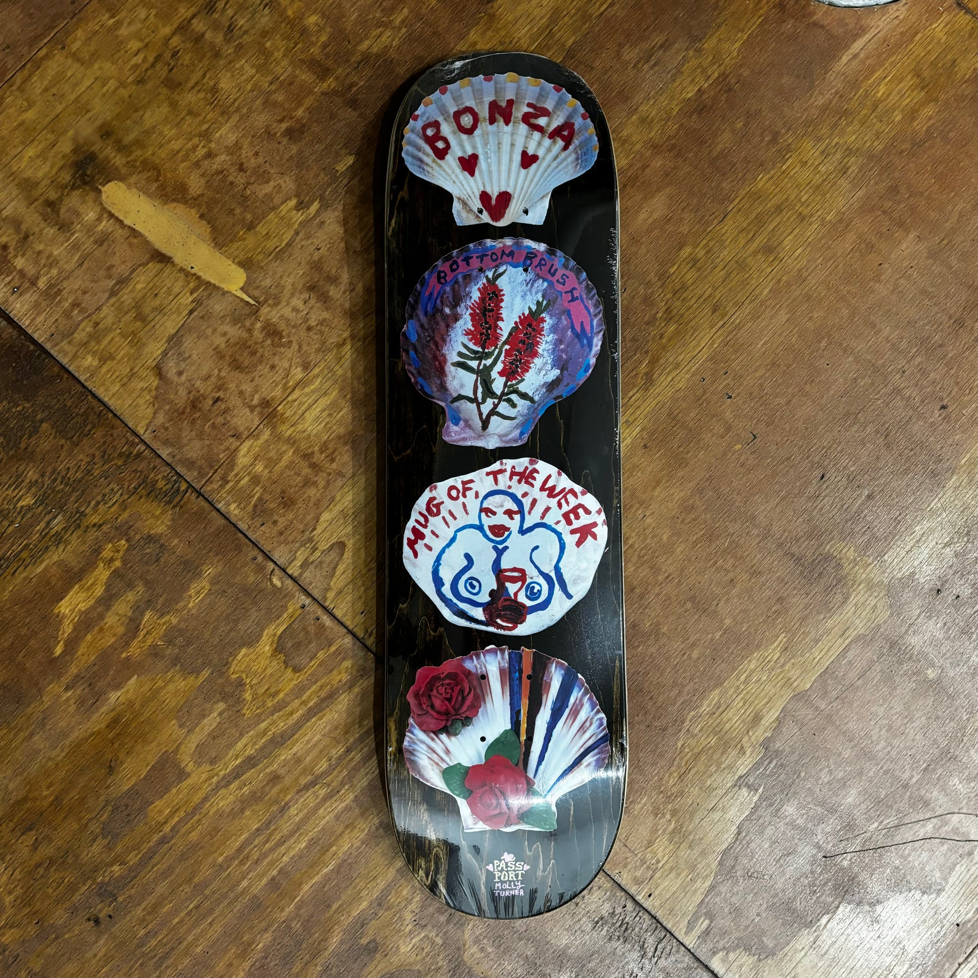 Image of four shells with hand drawn art on bottom of skateboard deck