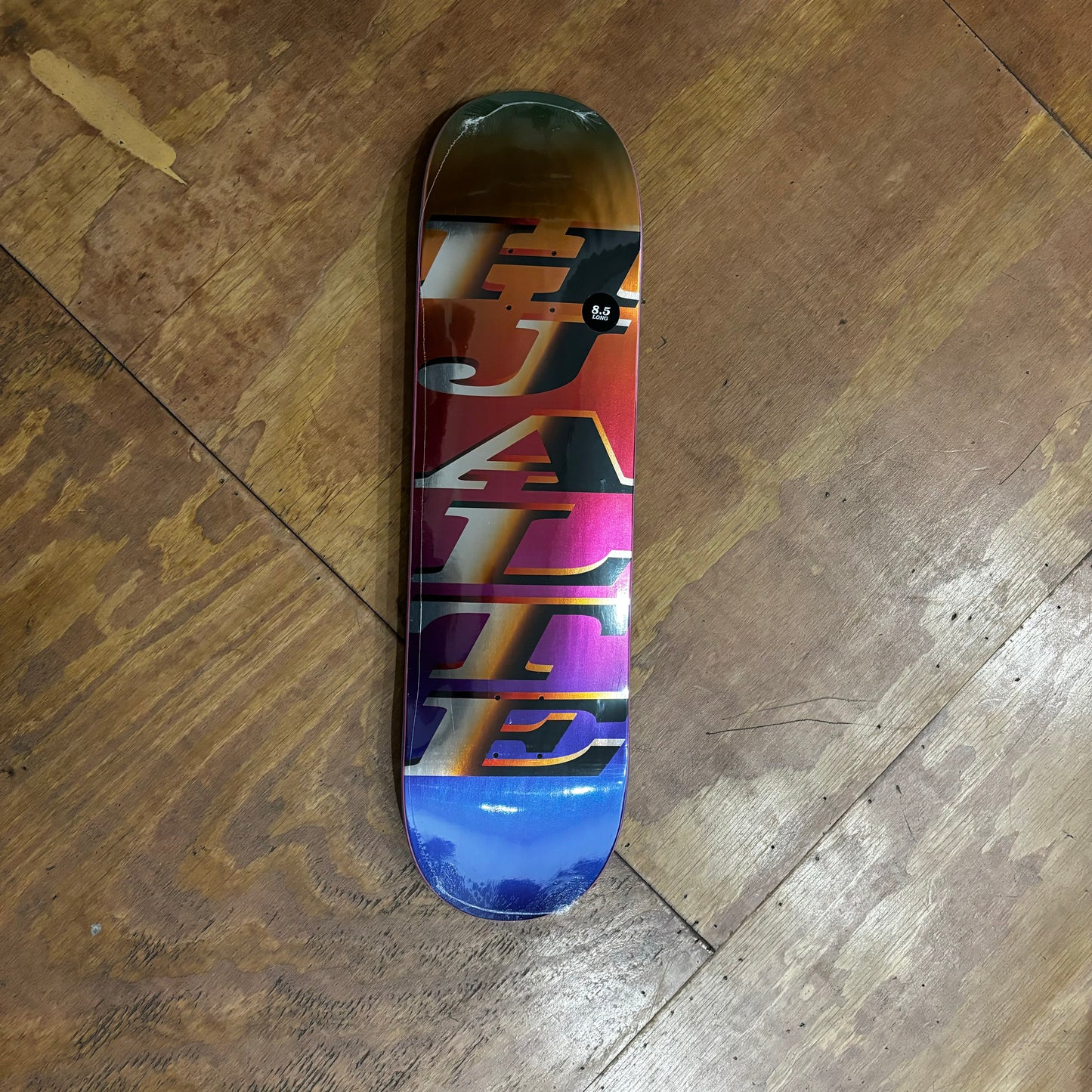 HJALTE printed vertically in metallic orange and silver on orange, red, purple and blue skateboard deck