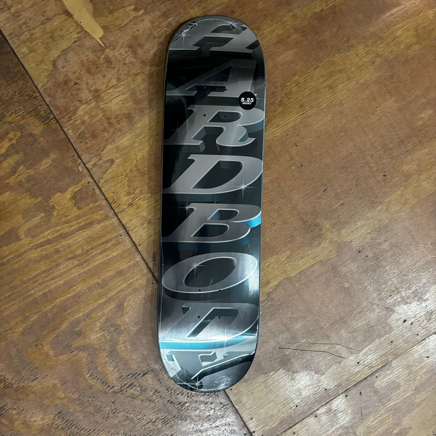 HARDBODY written in metallic silver and light blue on black/grey metallic skateboard deck