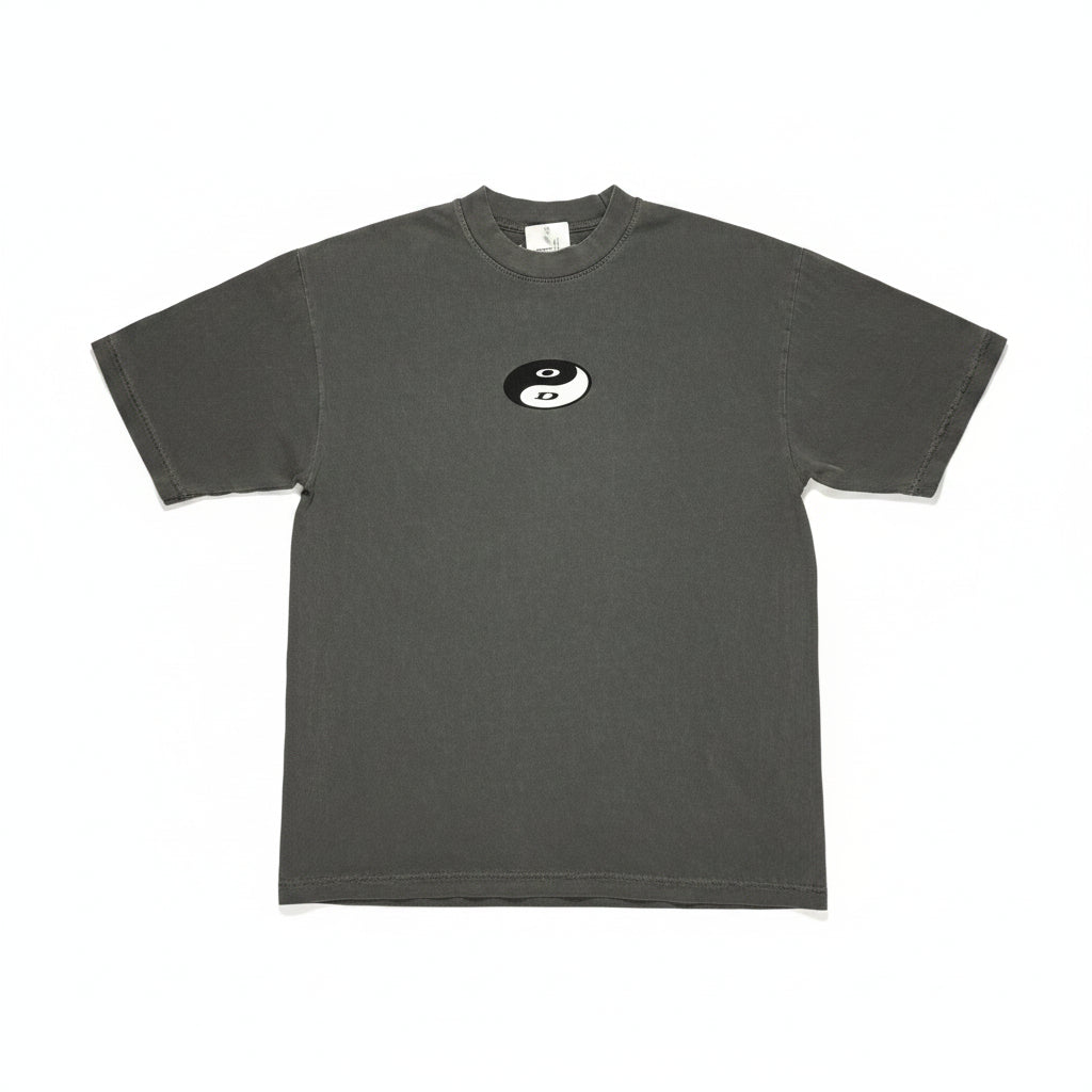 Gray t-shirt with a small yin-yang logo on a textured surface