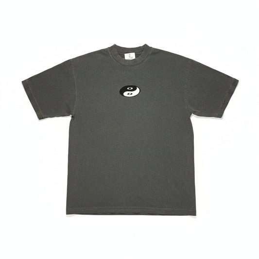 Gray t-shirt with a small yin-yang logo on a textured surface