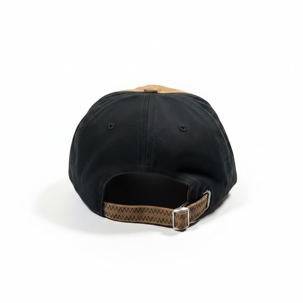 Black cap with a brown strap on a white surface