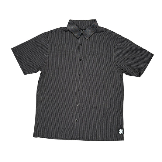 Black short-sleeve button-up shirt with a small logo on a white surface