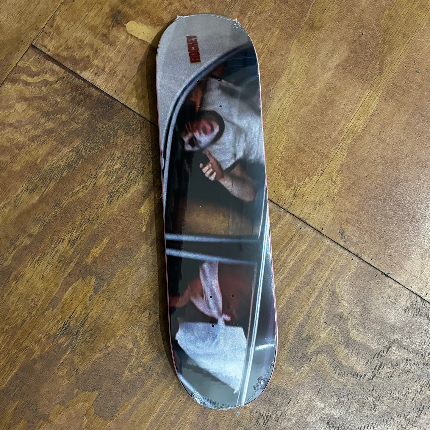 photo graphic on skateboard deck of kid in window of car making a face in a mask