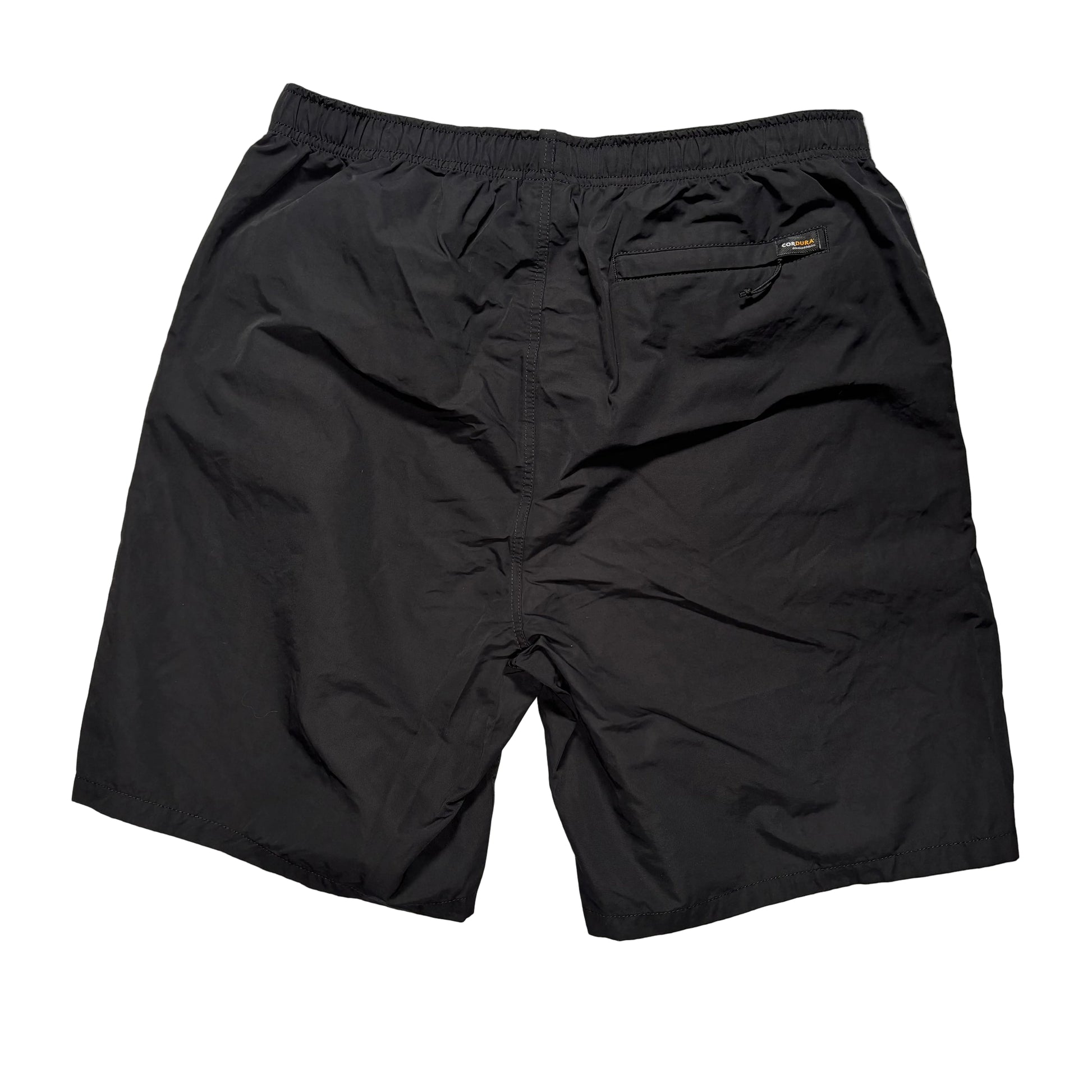 view of rear of Black elastic waist stussy shorts on a gray concrete surface