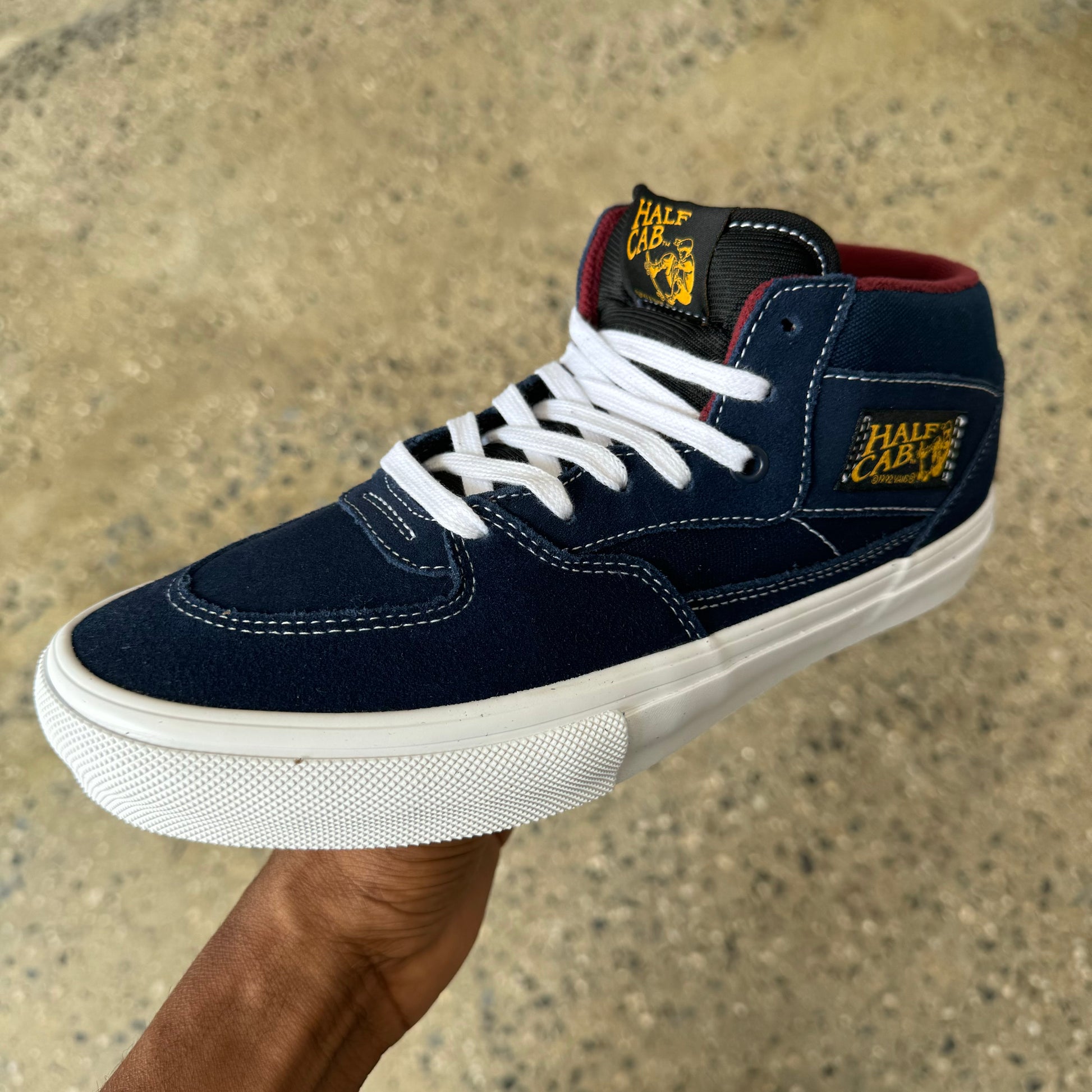 navy blue shoe with white stitching and burgundy inside with white rubber sole