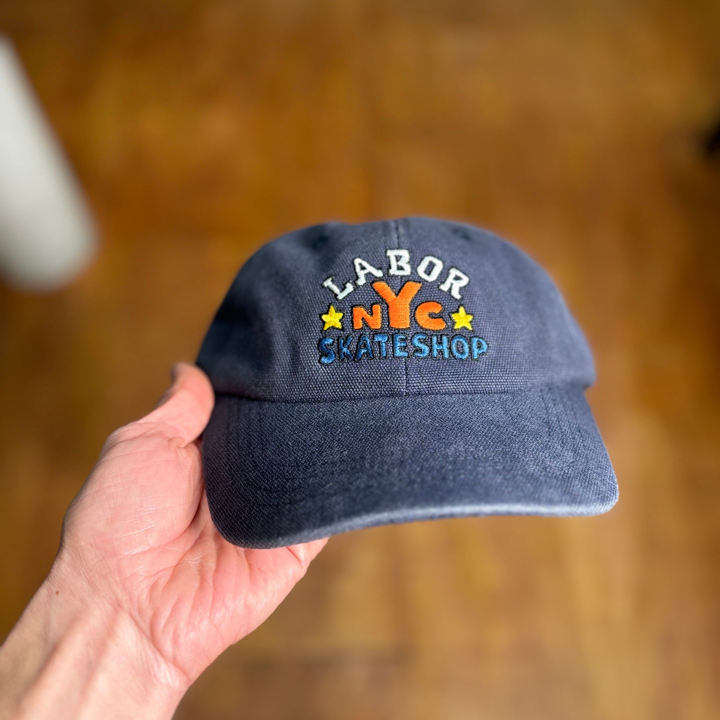 front view of blue canvas cap with LABOR SKATESHOP NYC embroidered on cap