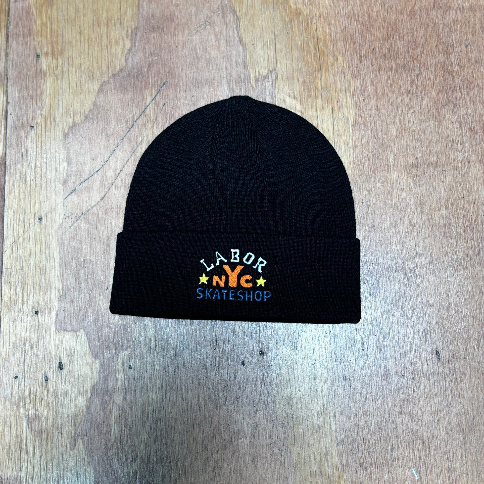 top down view of black acylic beanie with LABOR SKATESHOP NYC embrodered on front of beanie