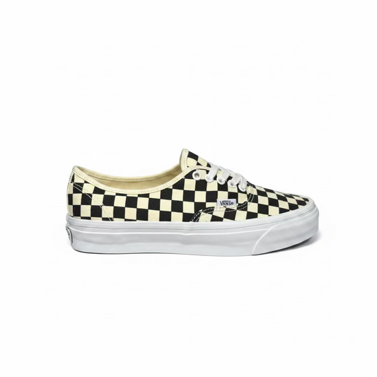 side view of black and white checkerboard deck shoe from vans, against white background