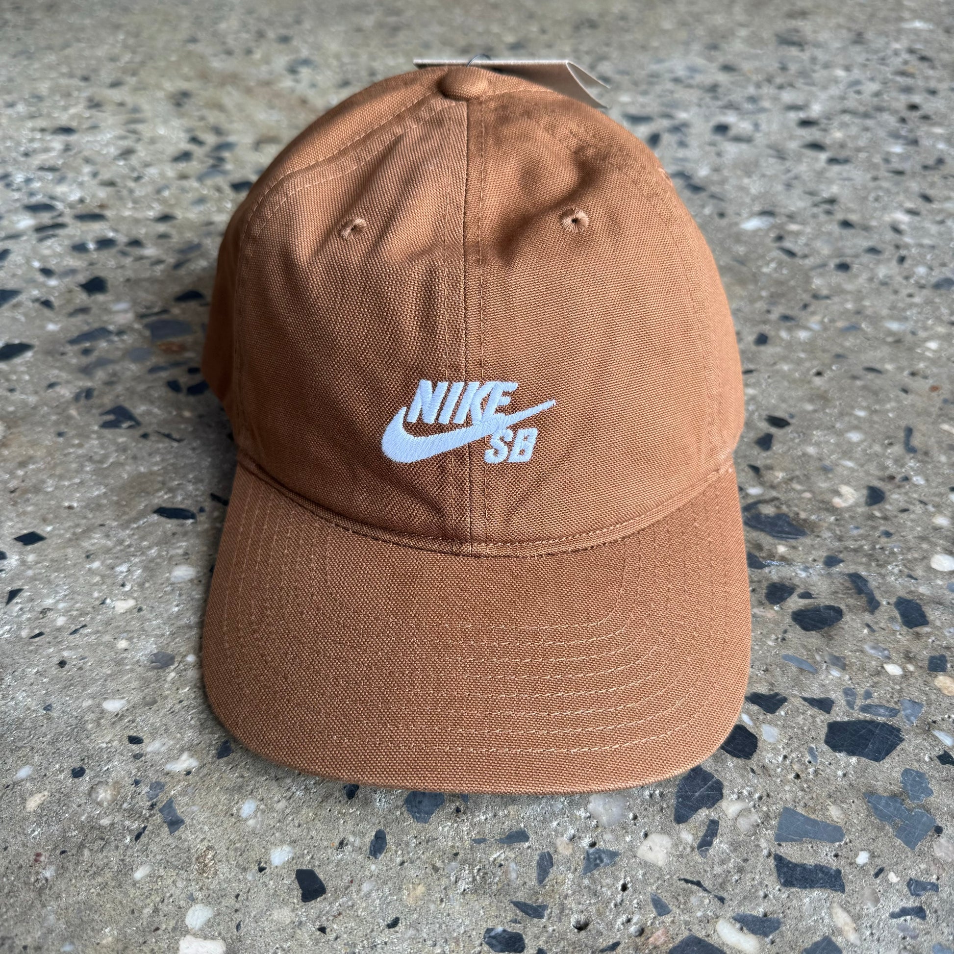 light brown colored unstructured cap with white nike sb logo in center