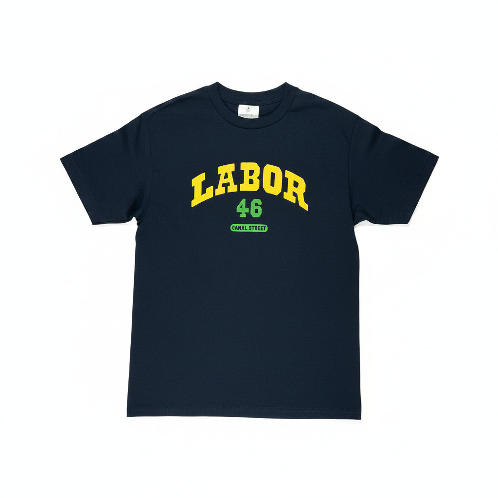 A navy short-sleeve t-shirt laid flat on a white surface, featuring 'LABOR 46' printed in yellow varsity-style lettering with a green outline and 'CANAL STREET' in green below.