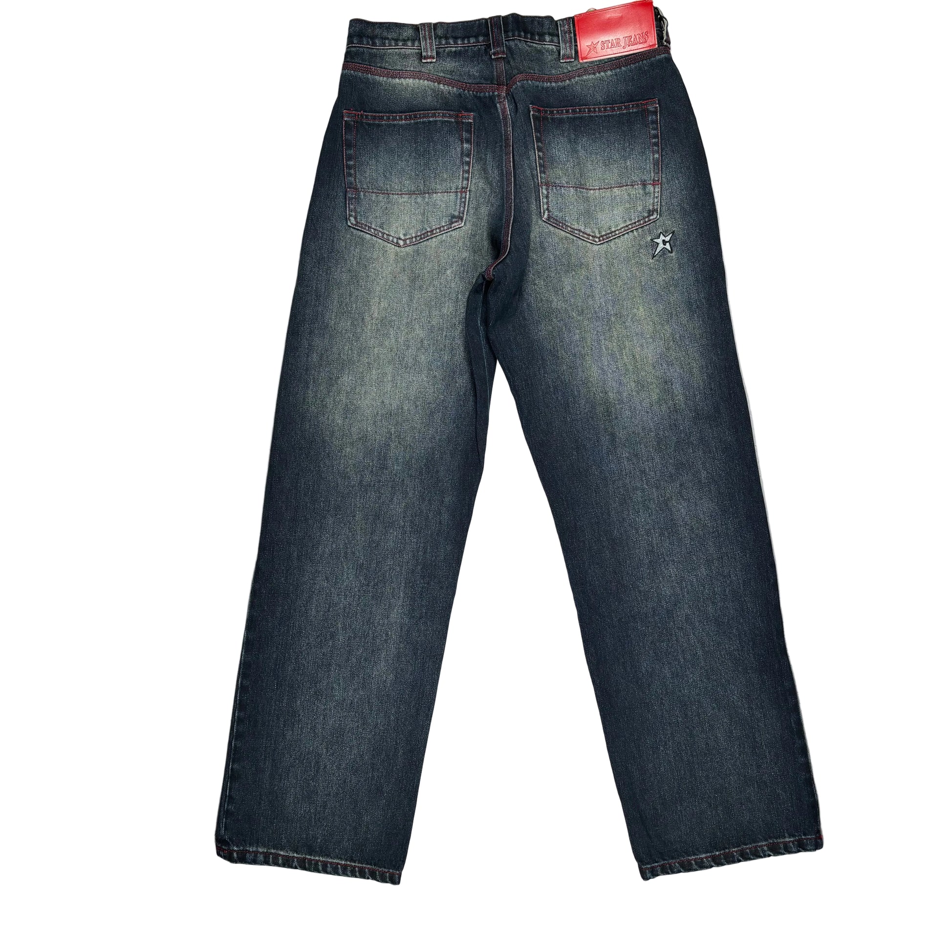 Back view of dark blue denim jeans laid flat on a white background. The jeans show faded whiskering and a small embroidered logo on the upper right back pocket, and a red leather wasitband patch