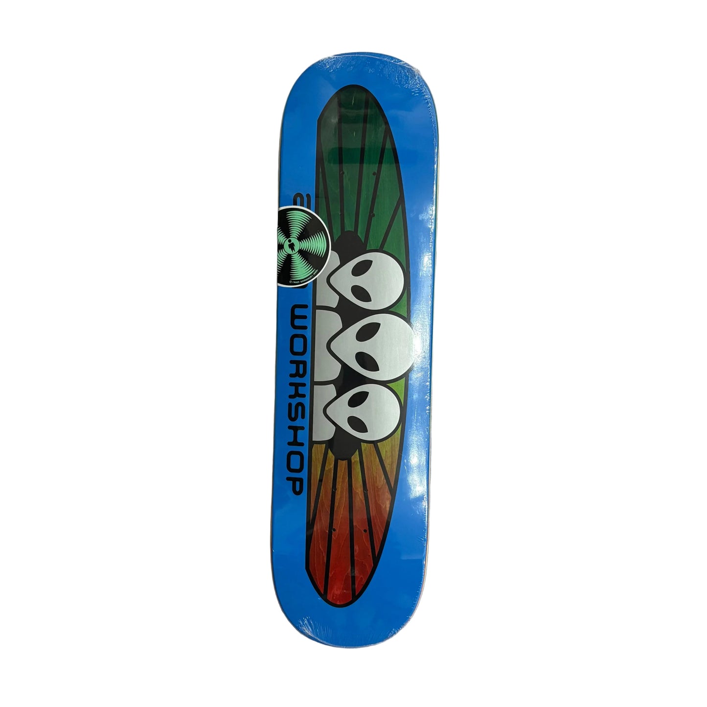 A skateboard deck with a blue border and a graphic of three white skulls on a green-to-red gradient background, with the brand name 'ALIEN WORKSHOP' printed vertically. The deck is photographed from above on a white background