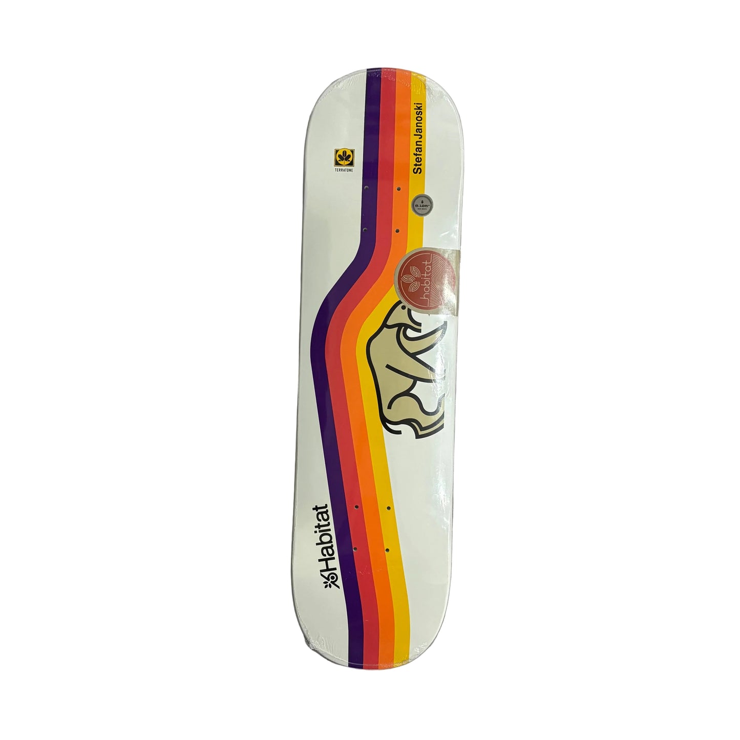 A skateboard deck with a white base, featuring a prominent diagonal rainbow stripe design in purple, orange, yellow, and red. A stylized bear graphic is printed on the upper deck, along with the brand name 'Habitat' and Pro rider name "Stefan Janoski'