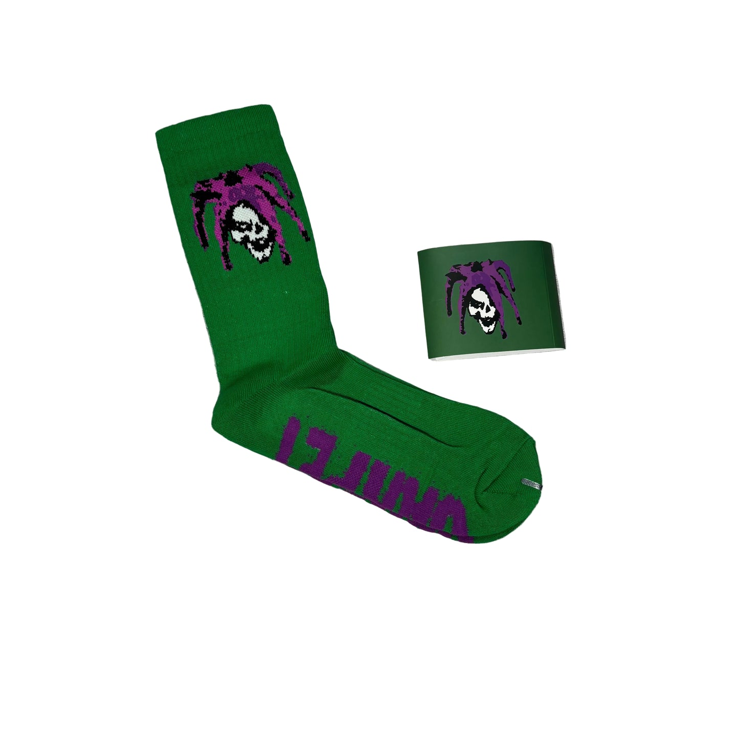 A pair of bright green crew socks with a purple and white skull-and-dreadlock graphic, shown on a white background with one sock laid flat and a paper sleeve with the dreadlock skull
