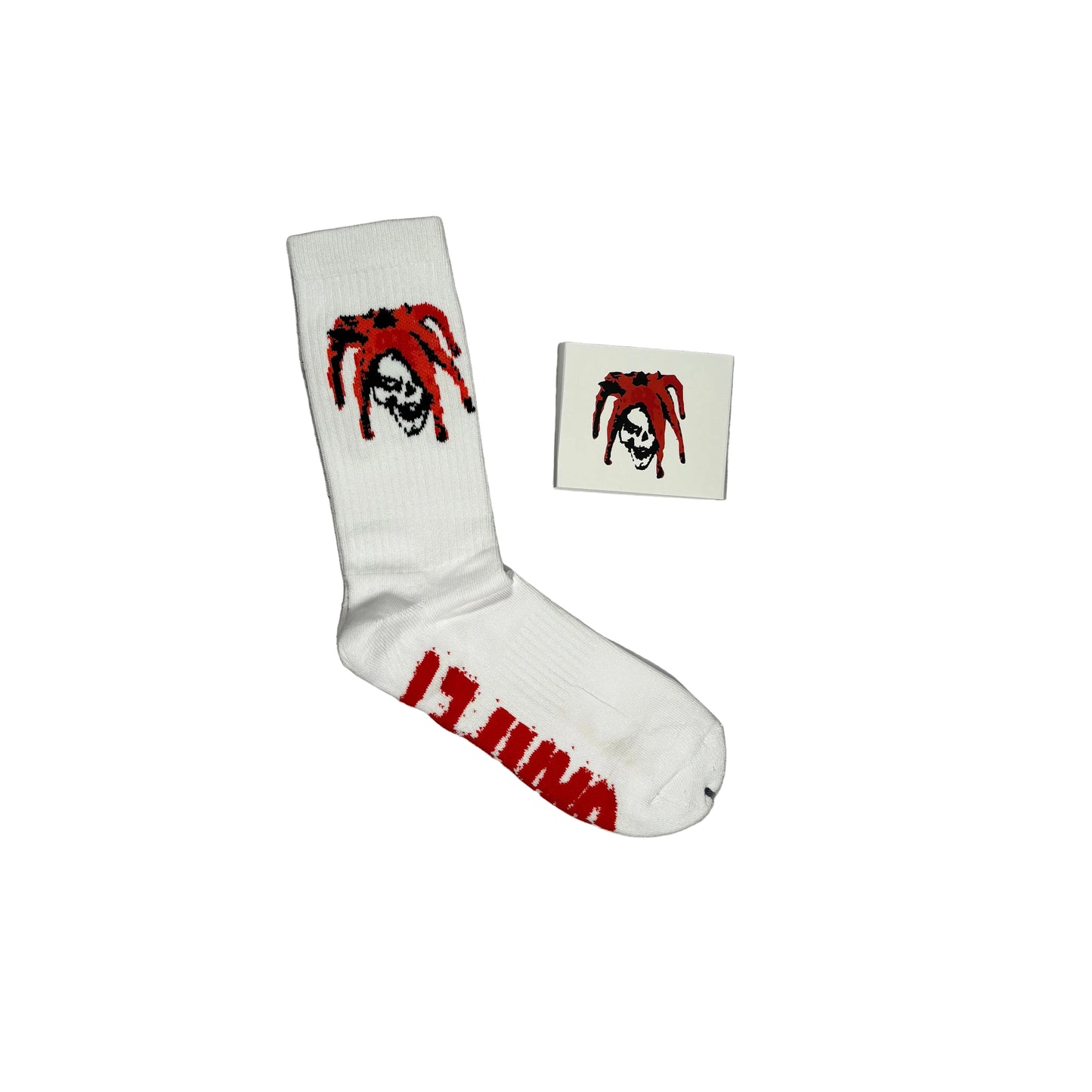 A pair of white crew socks with a red and white skull-and-dreadlock graphic, shown on a white background with one sock laid flat and a paper sock packaging sleeve with the dreadlock skull
