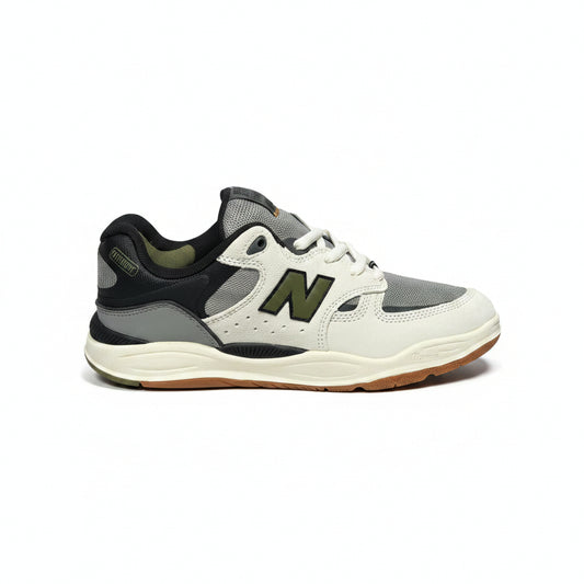 A New Balance sneaker in off-white, gray, and black with an olive green 'N' logo, shown from the side against a white background
