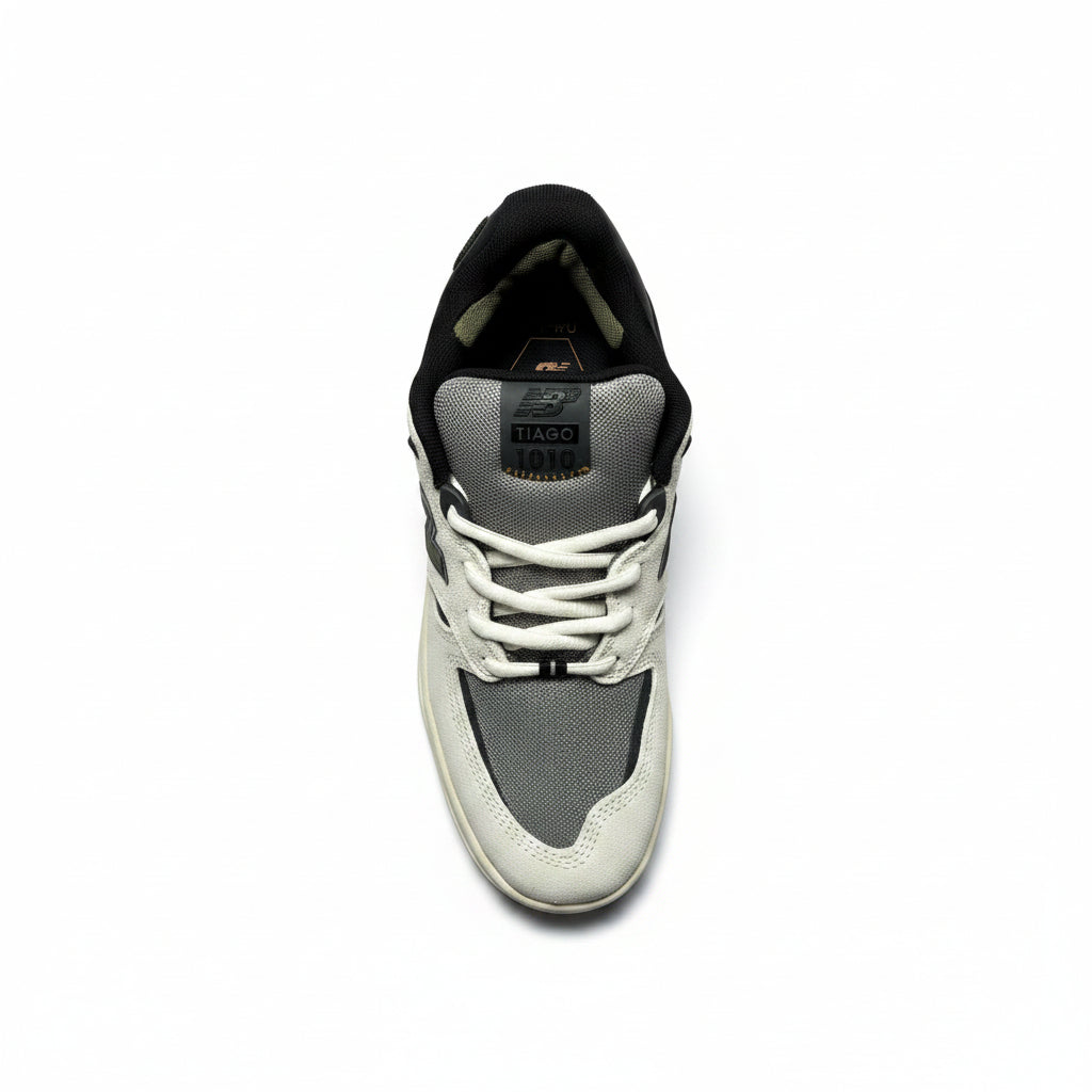 A single low-top sneaker shown from a top-down view on a white background. The shoe features a black collar, white laces, a white and gray mesh upper, and a cream-colored rubber sole.