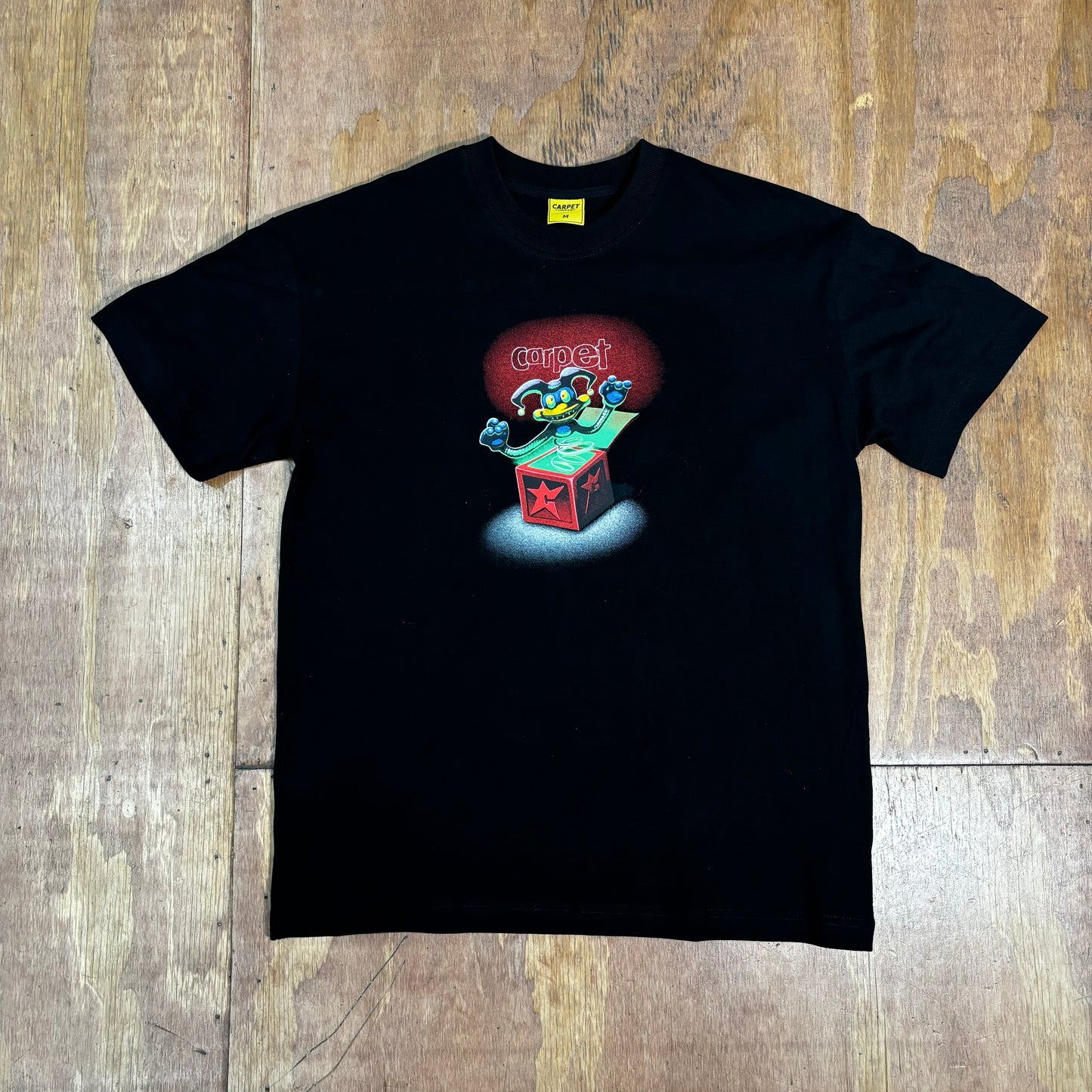 Front view of black t-shirt with center chest graphic of a jack in the box