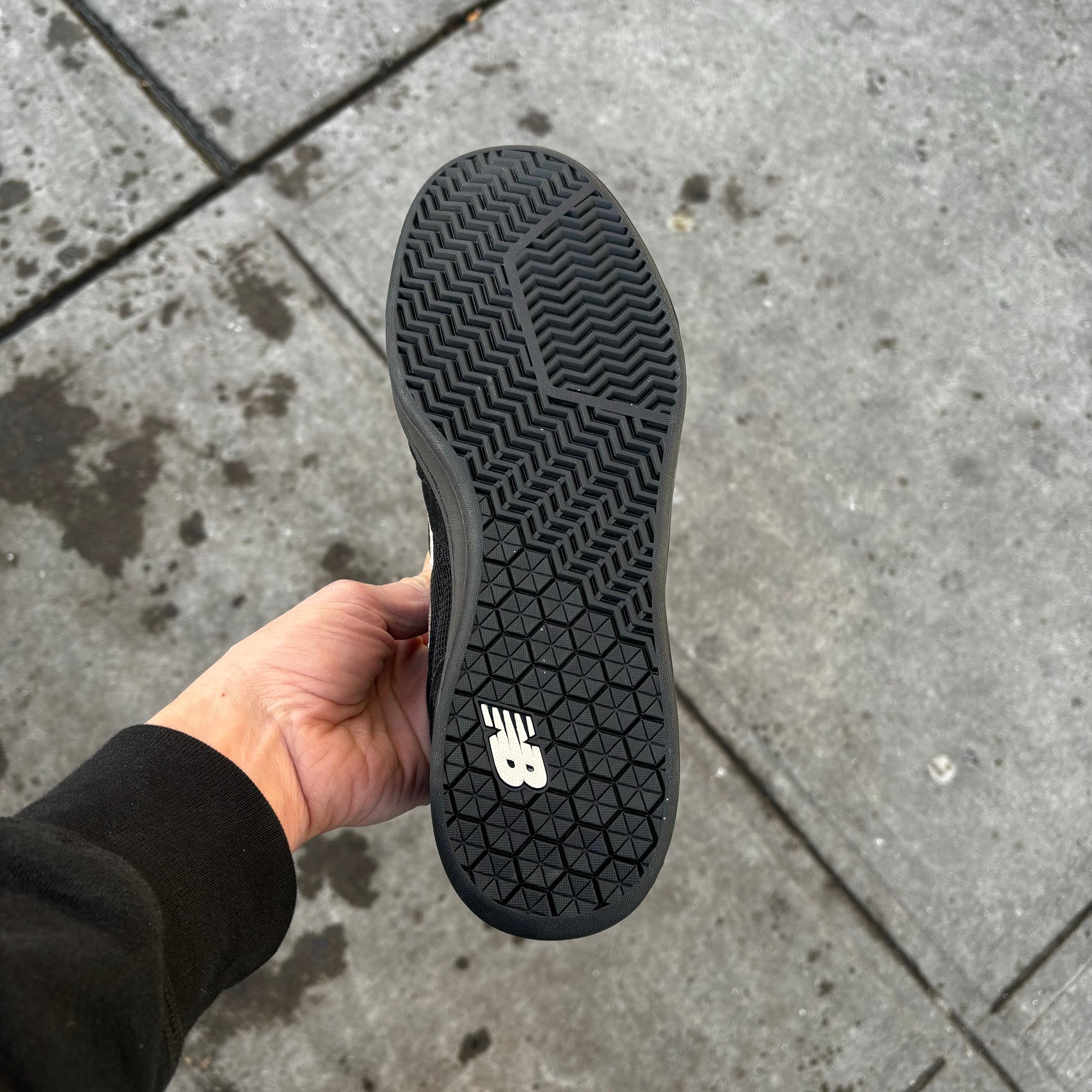 View of black rubber outsole on black/white suede skateboard sneaker