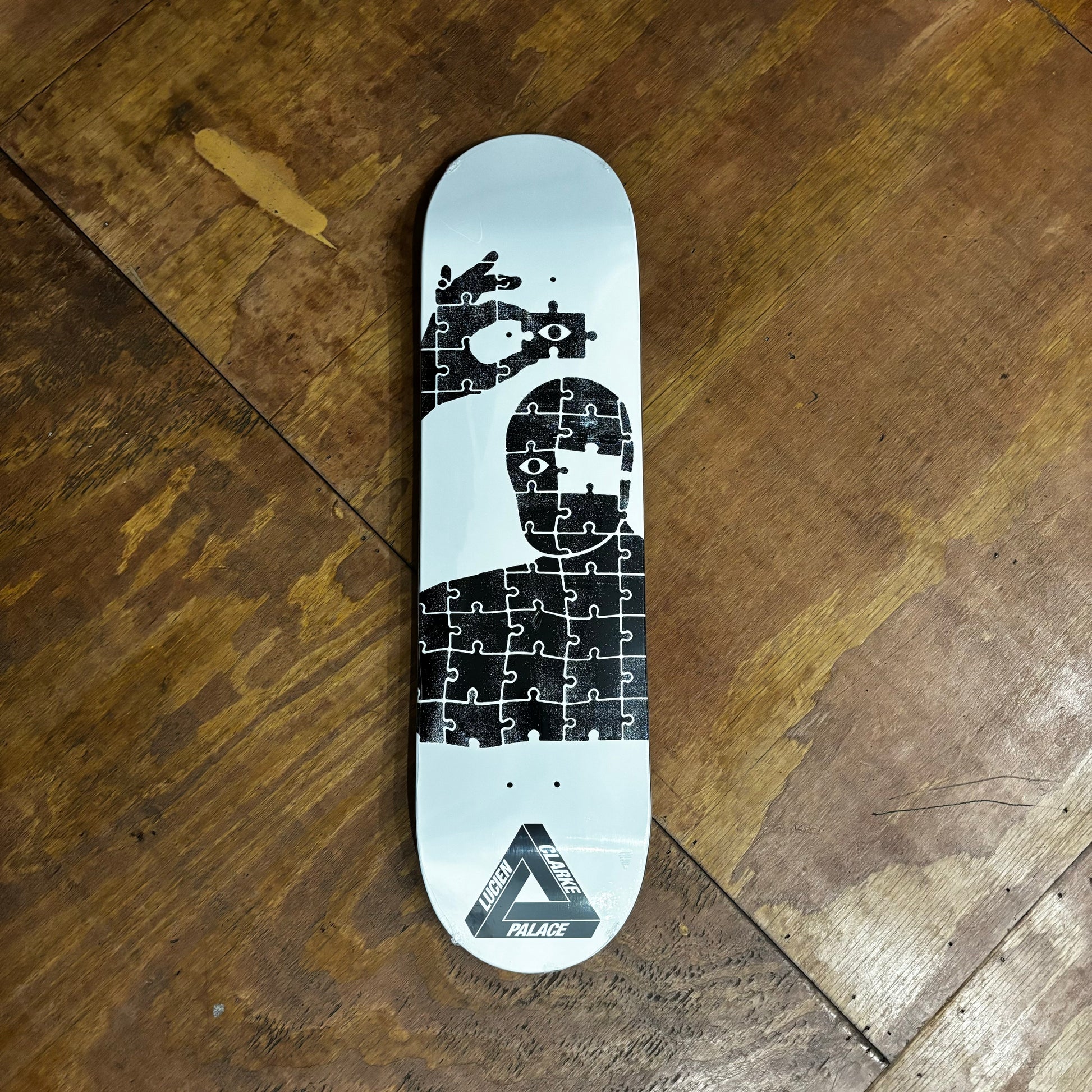 white and black skateboard deck with graphic of man as a puzzle, with one missing piece, and hand reaching out with the missing piece