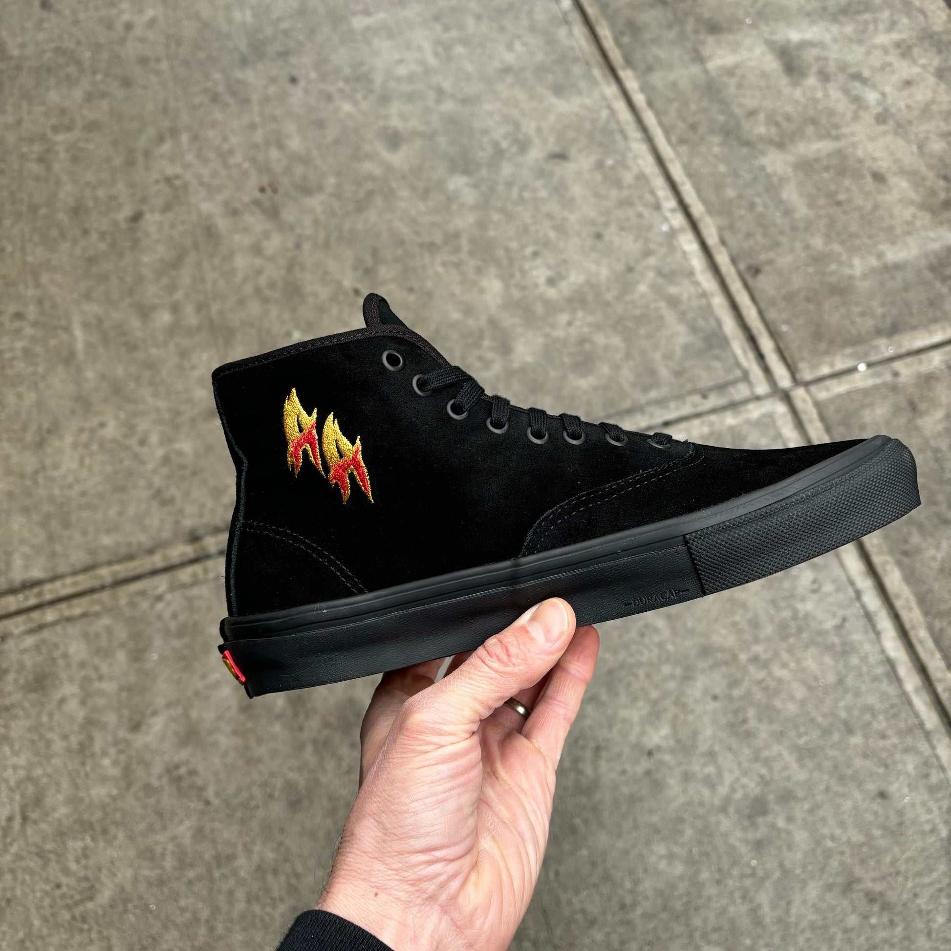 side view of black suede mid top skateboard sneaker, with AA embroidery 