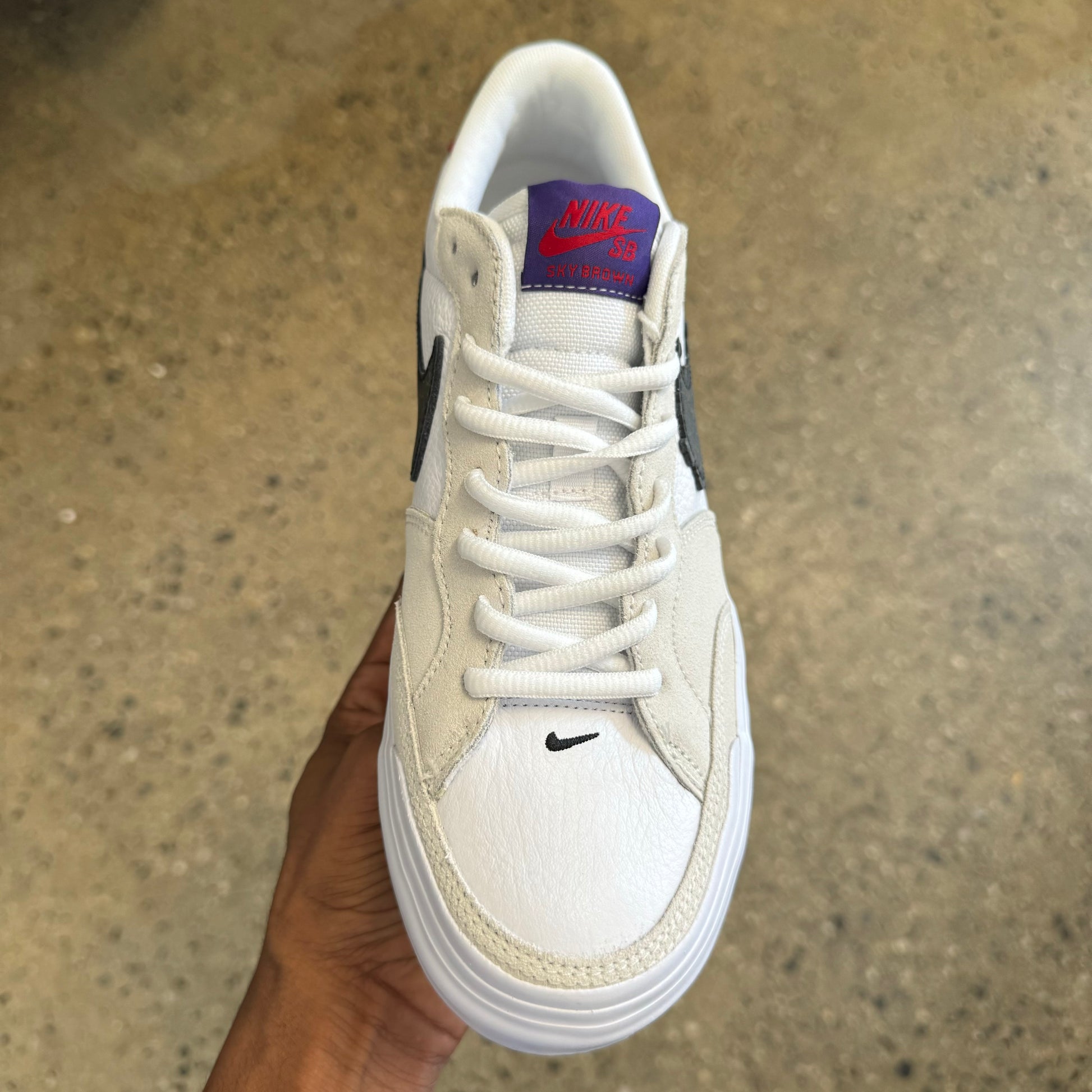 front view of the shoe. white shoe laces. purple and red label on tongue