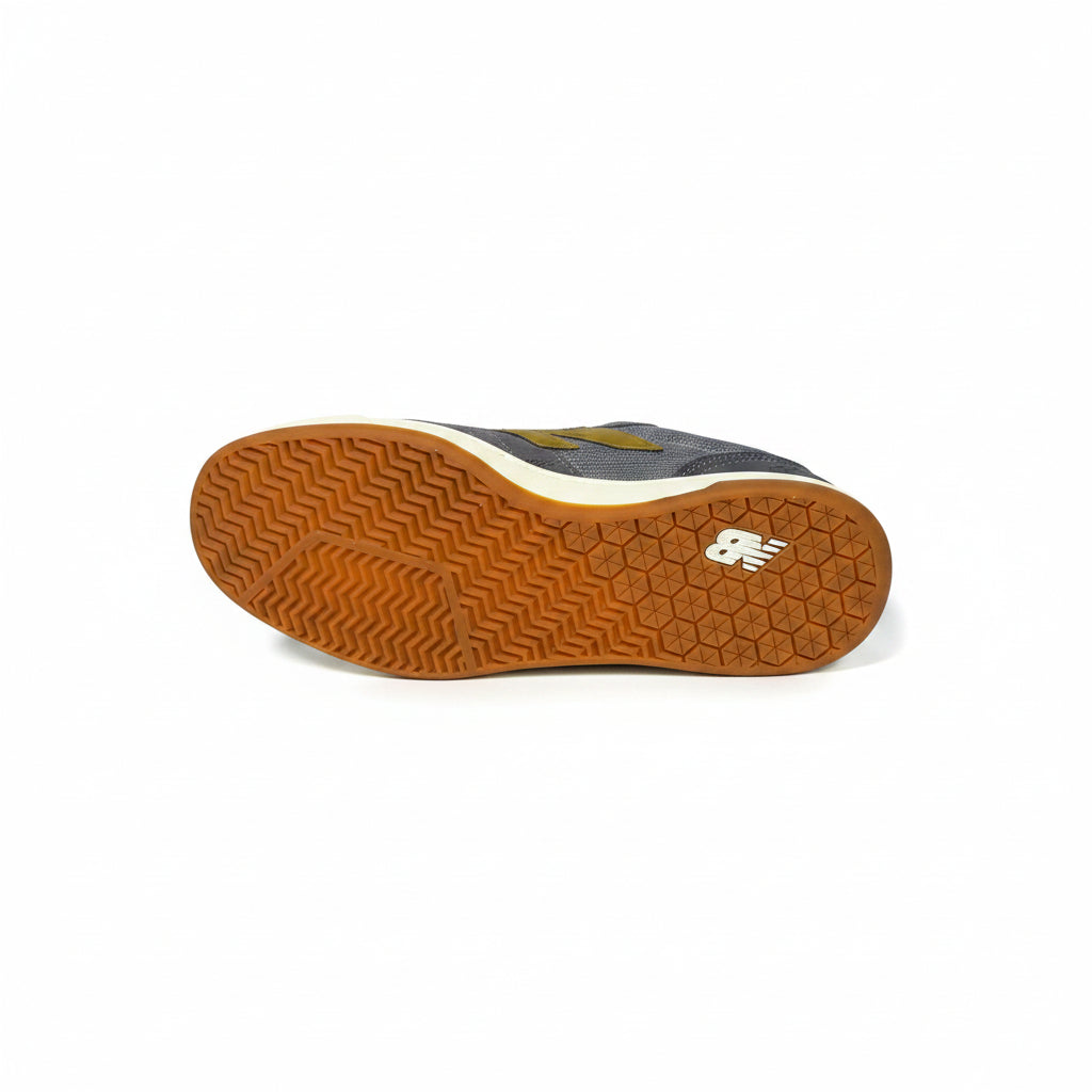 The outsole of a New Balance sneaker, showing a brown gum rubber tread with a white New Balance logo and a white midsole, photographed against a white background