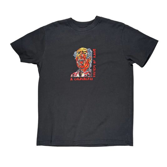 A black short-sleeve t-shirt laid flat on a textured gray surface, featuring a colorful graphic of a screaming face with red and orange tones and the text 'SYSTEM OF A RAGE' and 'A COLORLESS' printed on the front.