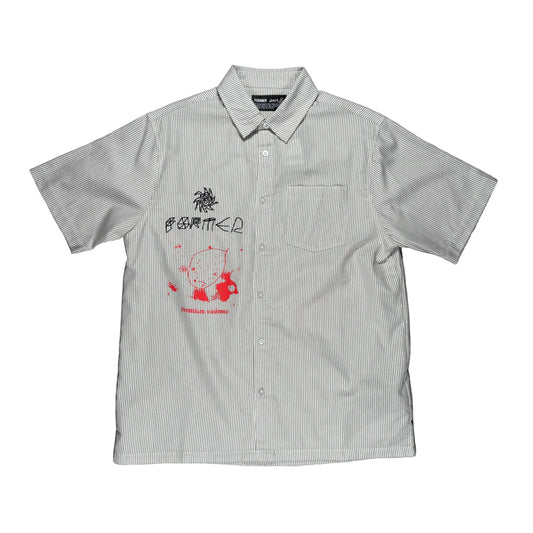 A short-sleeve button-up shirt laid flat on a textured gray surface. The shirt has a very fine vertical stripe pattern in off-white and a muted green-gray, featuring a red and black graphic print on the left chest with the text former premium violence