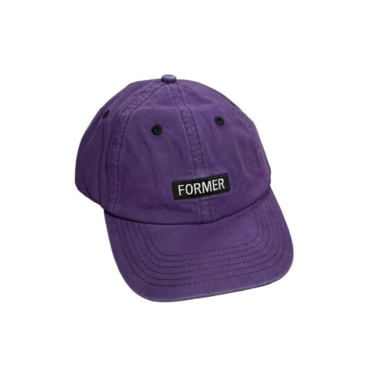 A purple cotton baseball cap with a black rectangular patch on the front that reads 'FORMER' in white text, photographed on a white background.