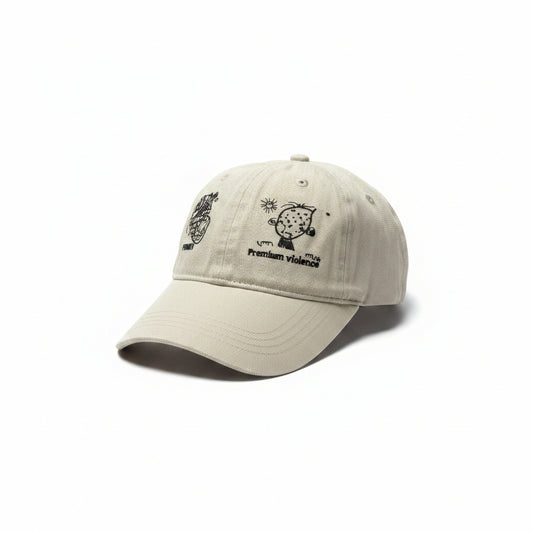 A light beige baseball cap with black embroidered graphics on the front panels, resting on a white surface.