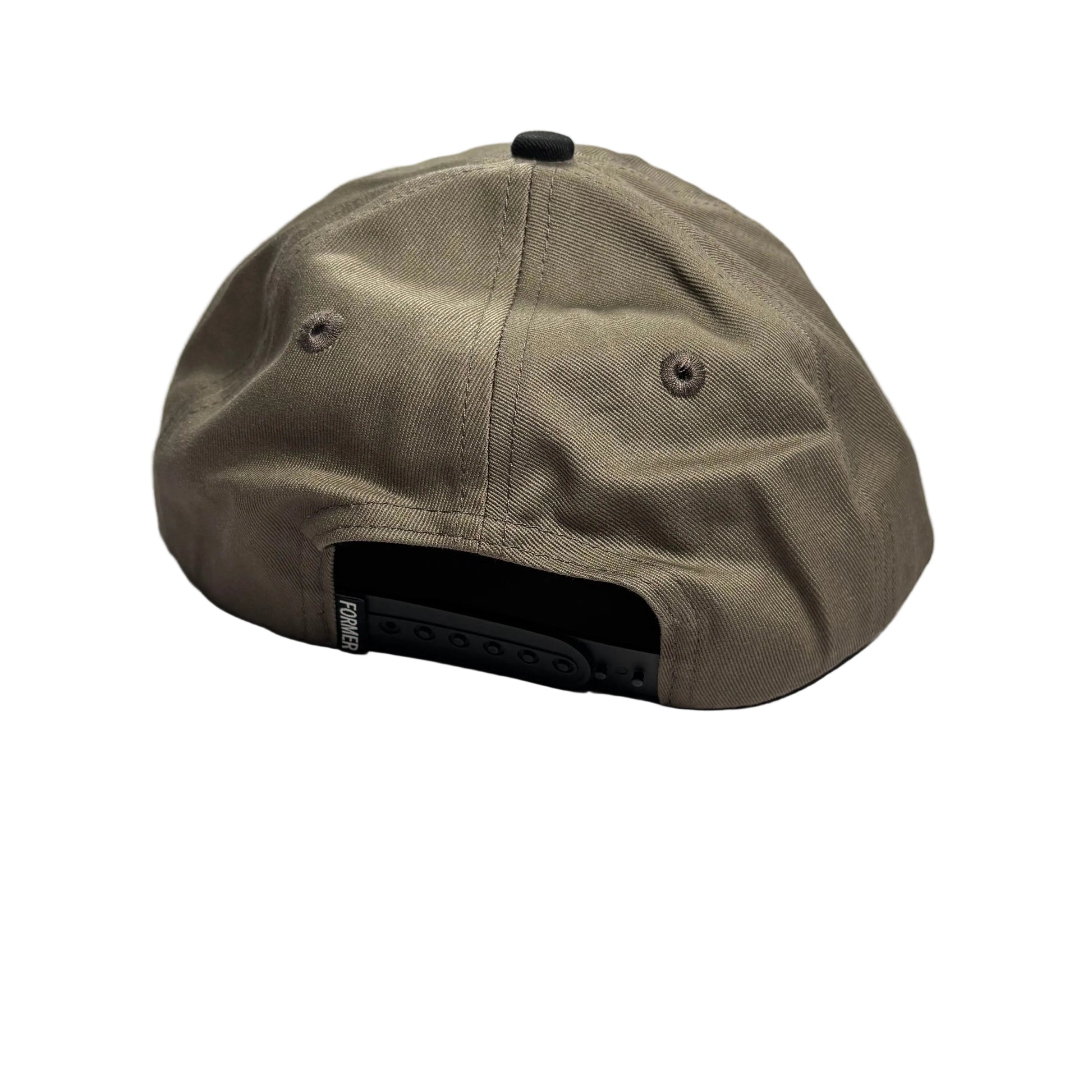 A brown baseball cap viewed from the back, resting on a textured gray concrete floor. The cap features a black snapback closure and a small black button on top.