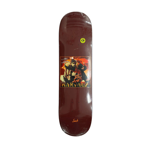 A dark brown skateboard deck with a graphic print of two characters and the text 'NARVAEZ' on the underside, resting on a white background