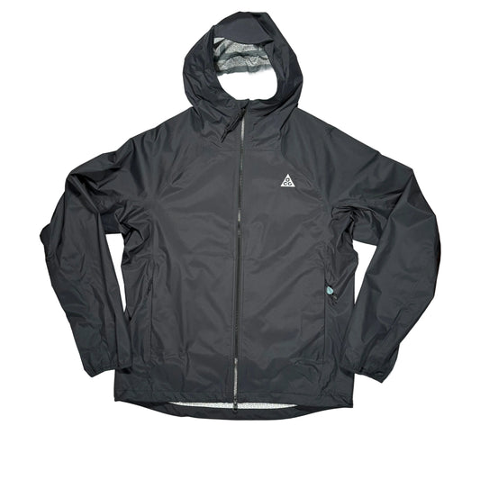 A black hooded zip-up jacket laid flat on a white surface with a small white triangular ACG logo on the left chest, photographed from above on a white surface.