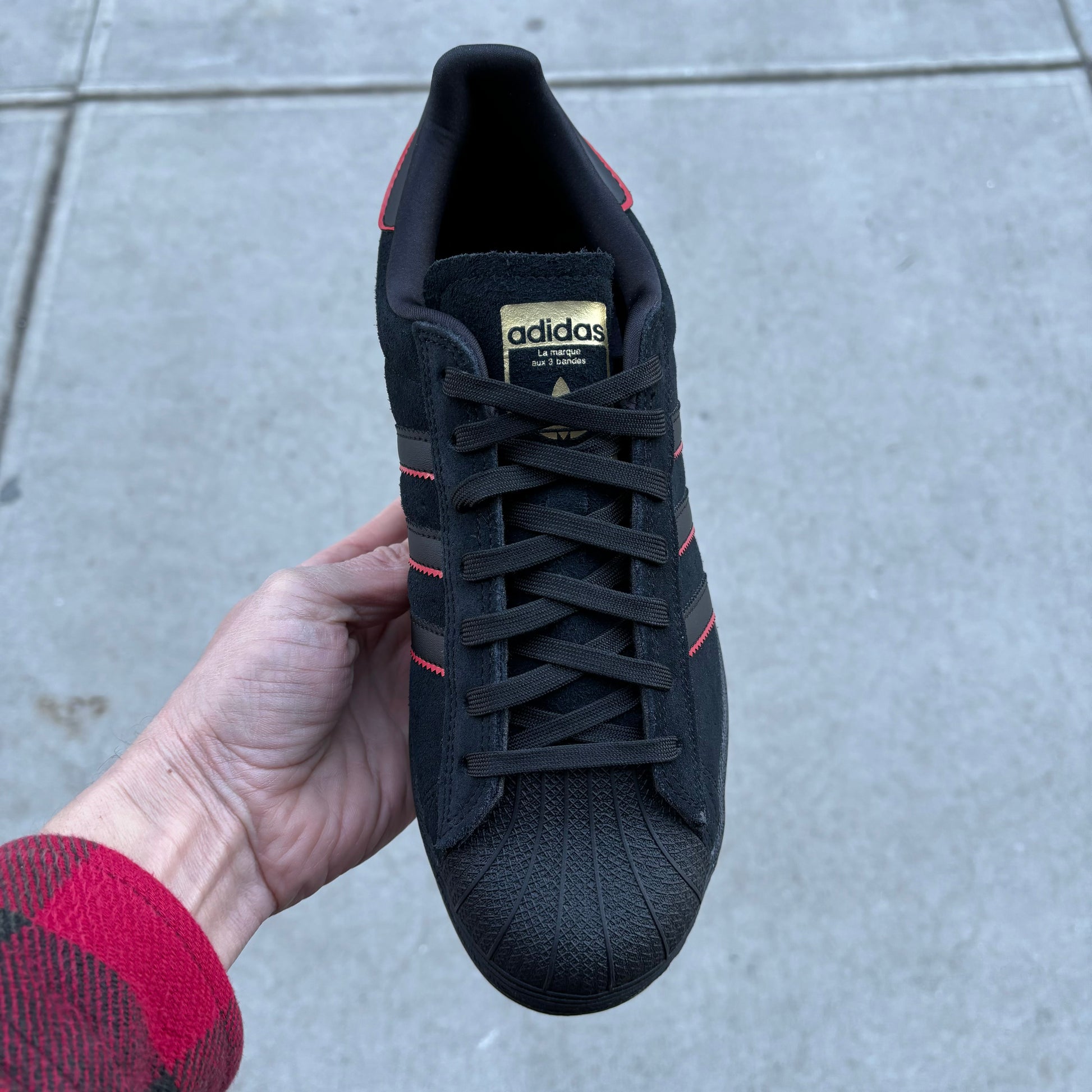 top down view of black, red and gold lowtop suede skateboard sneaker