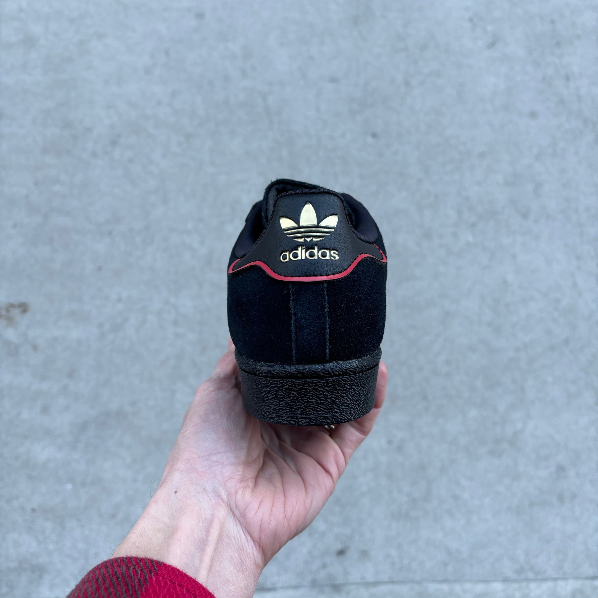 view of heel tab with adidas tre foil logo in gold on leather patch on back of sneaker