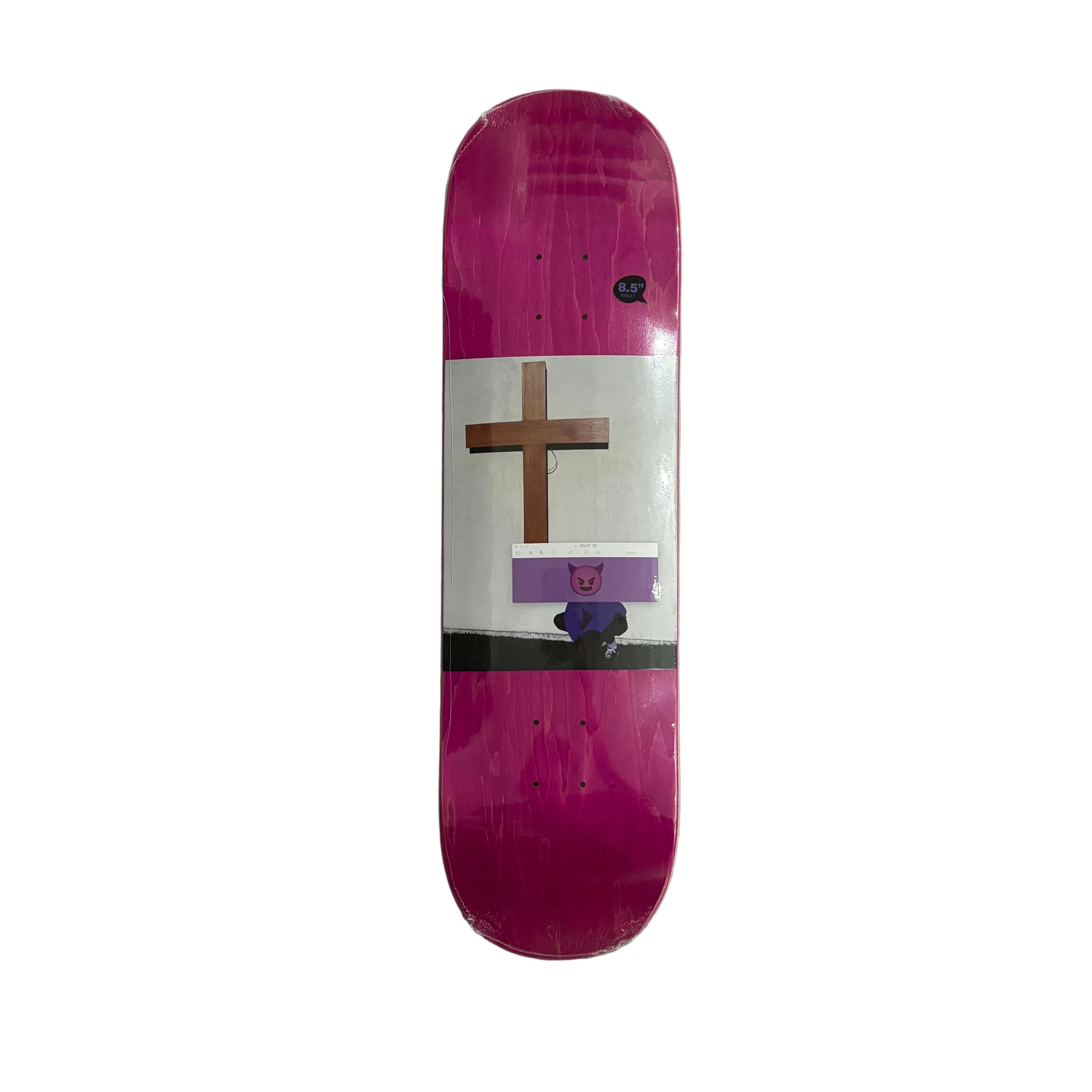 A skateboard deck with a vibrant magenta-pink graphic design, featuring a white cross, a purple banner, and a small cartoon character, displayed vertically on a white surface.