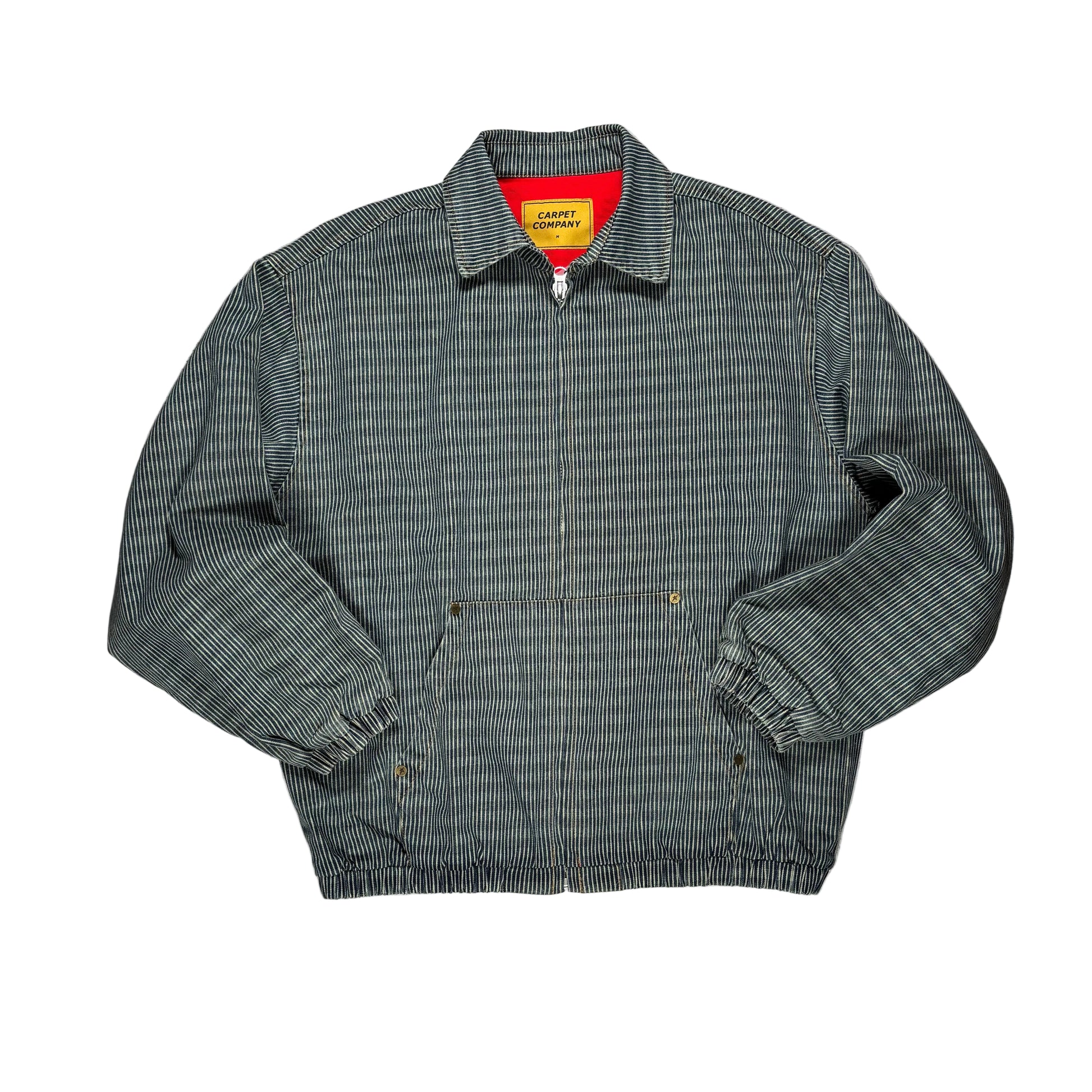A vintage-style work jacket with a fine gray and white striped pattern, featuring a zippered front, elasticized cuffs and hem, and a bright red inner collar lining with a yellow 'CARPET COMPANY' brand label.