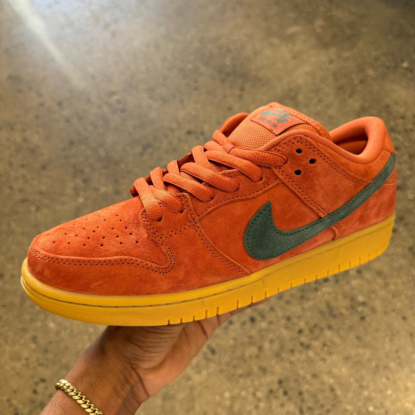 burnt orange shoe with dark green logo and gum sole