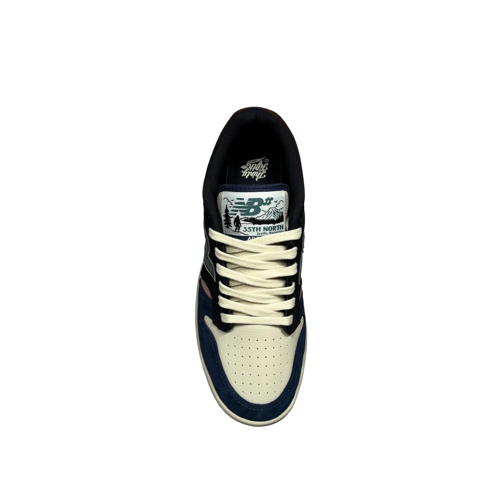 A single New Balance sneaker shown from a top-down view, featuring a cream and navy blue colorway with white laces and a white background.