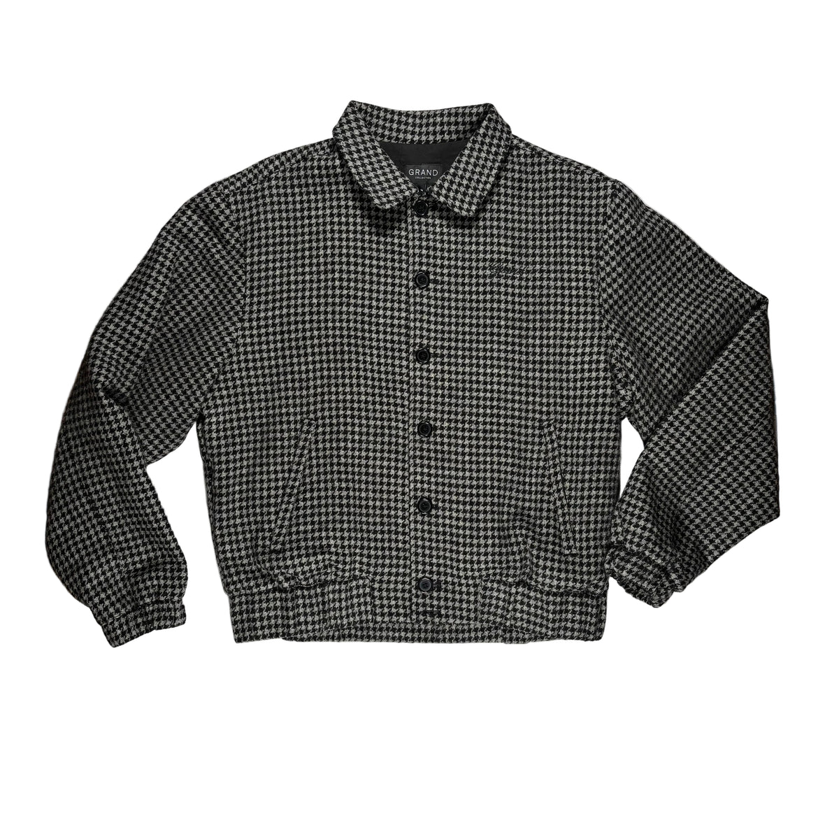 A black and white houndstooth button-up jacket with a pointed collar, laid flat on a white background 