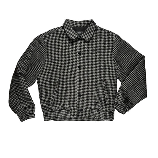 A black and white houndstooth button-up jacket with a pointed collar, laid flat on a white background 