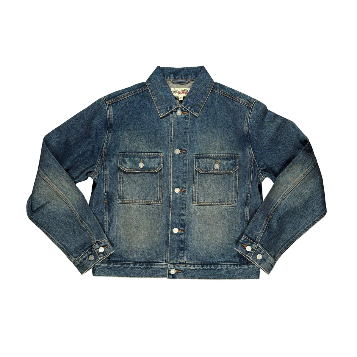 A blue denim jacket laid flat on a  white surface. The jacket features a classic collar, button-down front, and two buttoned chest pockets.