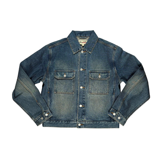 A blue denim jacket laid flat on a  white surface. The jacket features a classic collar, button-down front, and two buttoned chest pockets.