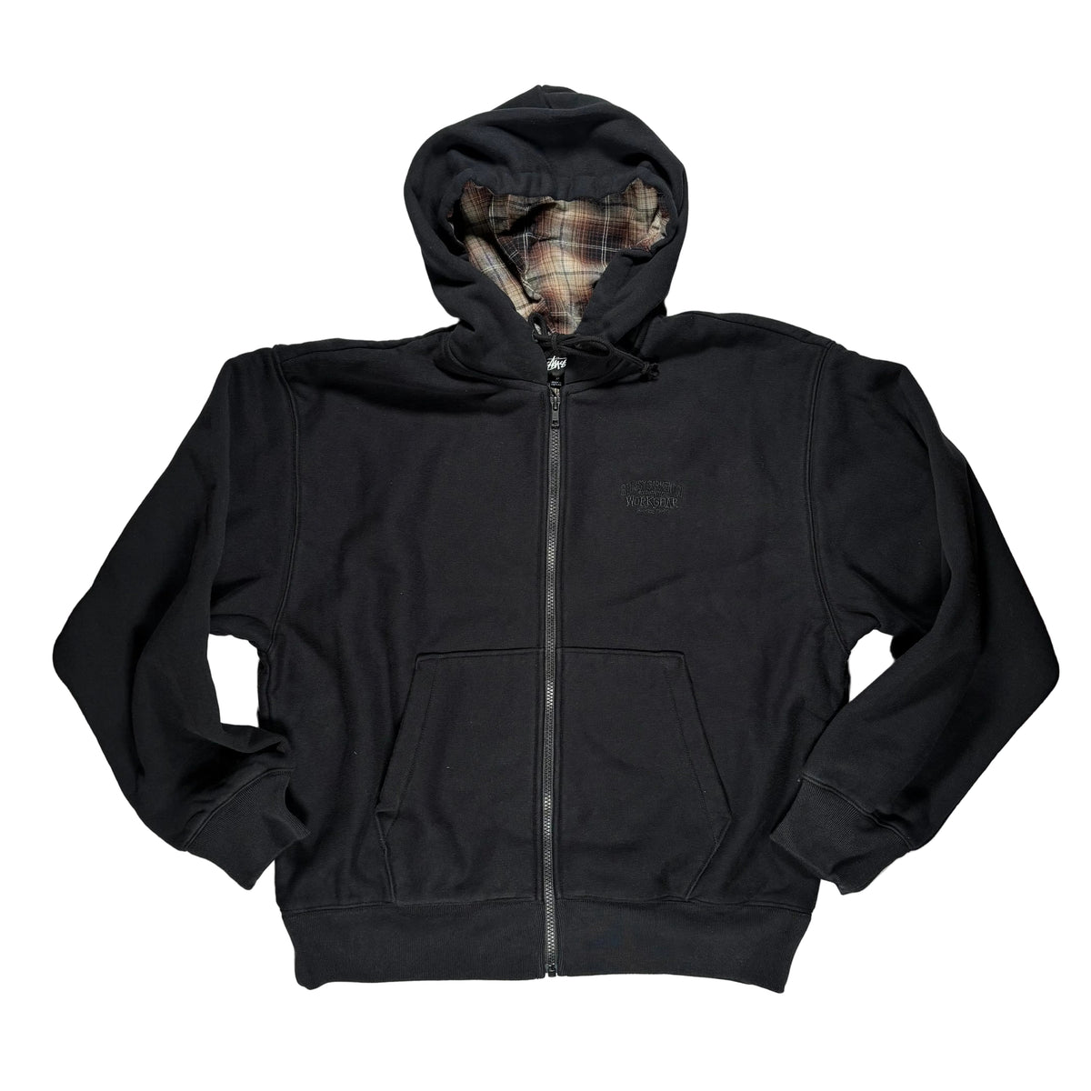 A black zip-up hoodie laid flat on a white surface. The hoodie features a small tonal embroidered logo on the left chest, a front zipper, and a hood with a plaid lining visible inside.