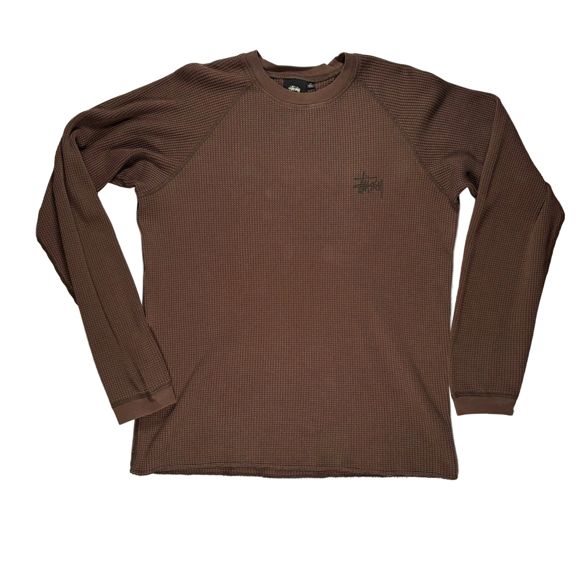 A brown ribbed long-sleeve crewneck shirt by Stüssy, featuring the brand's signature  logo on the left chest, laid flat on a white surface.